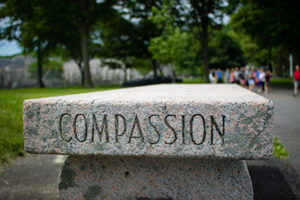 The word compassion carved into the side of a stone bench