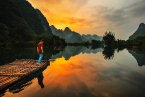 Man stands next to river at sunrise