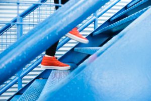 feet in red tennis shoes walking up blue stairs