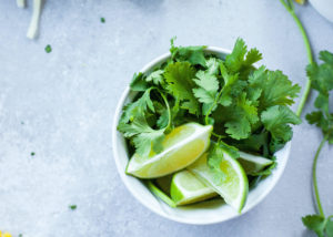 a bowl of lime wedges and sprigs of cilantro