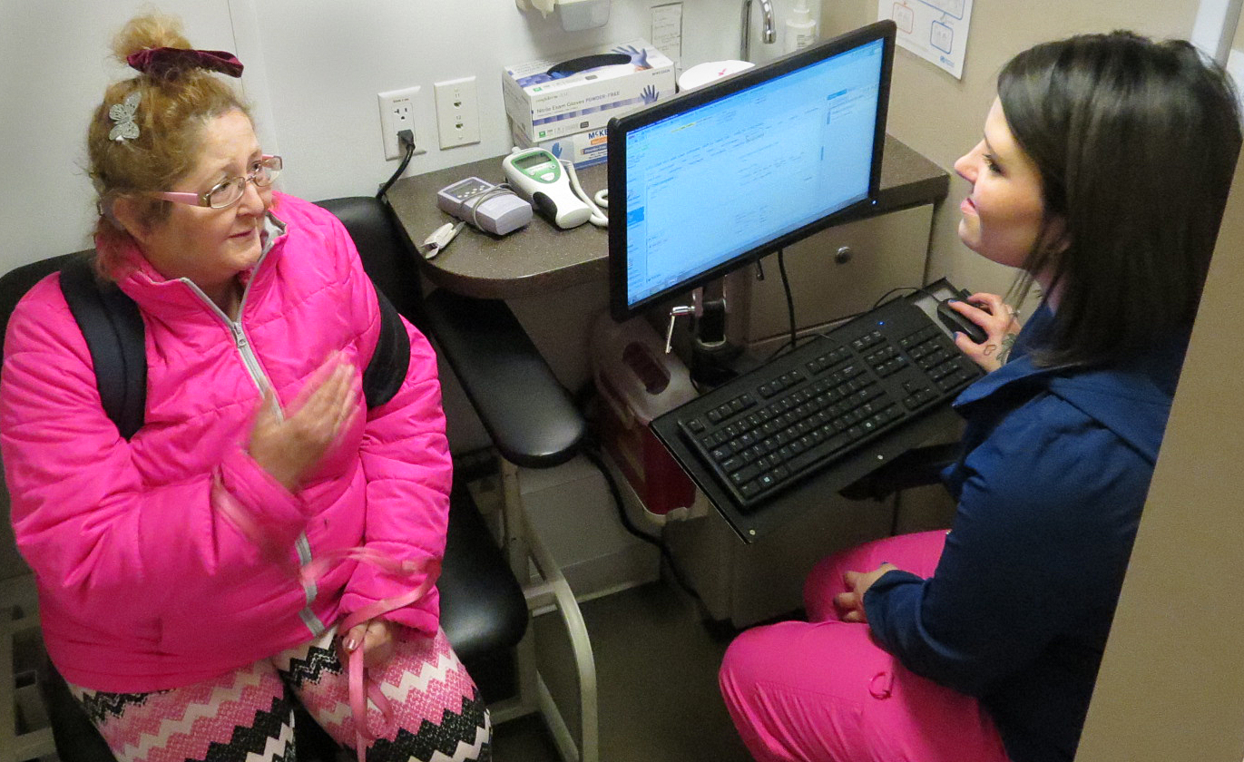 Mobile center employee Trisha Ross talks with a patient on the mobile center during a stop at Kelly Shelter in Medford.