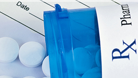 Blue prescription bottle with white pills and prescription.