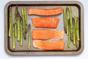 salmon fillets and asparagus on a baking sheet